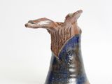 a blue vase with a bird on it on a white surface