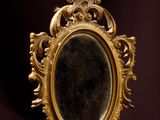 a small mirror sitting on a wooden table with a black background