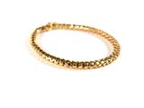 a close up of a gold bracelet on a white surface