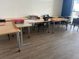 Il y a de nombreuses tables et chaises dans cette salle de classe, avec un ordinateur portable posé sur chaque bureau.
