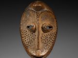 une image représentant un masque en bois posé sur un socle noir
