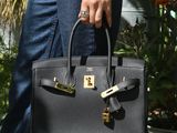 someone is holding a black purse and walking down a sidewalk