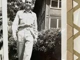 a black and white photo of a man standing in front of a house