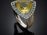 a close up of a ring with a yellow topazr and blue topazr