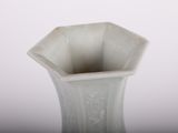 a white vase sitting on a table with a white background