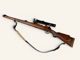 an old rifle with a wooden barrel and a sling on a white background