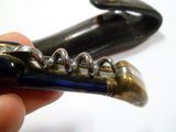 une main tenant un décapsuleur avec un tire-bouchon à l'intérieur