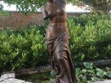 une statue représentant une femme debout sur un bloc de pierre