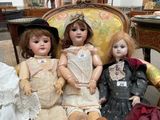 three dolls sitting next to each other on a chair