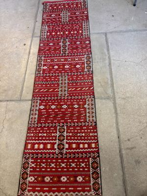 un long tapis rouge posé à même le sol, avec une chaise à l'arrière-plan