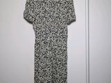 black and white floral dress hanging on a hanger in front of a white wall