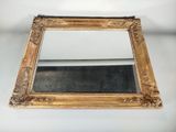 un miroir avec un cadre doré posé sur une surface blanche