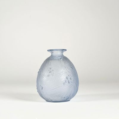 un vase en verre bleu posé sur une surface blanche