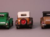 three toy cars sitting side by side on a gray surface