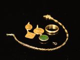 quelques bijoux dorés et verts posés sur une surface noire