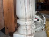 a white marble vase sitting on the ground next to a wooden pole