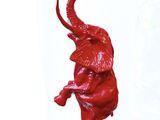 une sculpture rouge représentant un éléphant, posée sur un socle