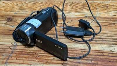 a video camera sitting on a wooden table with a charger attached to it