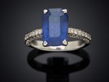 a blue sapphire and diamond ring on a black surface