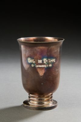 an old silver cup sitting on top of a table next to a black background