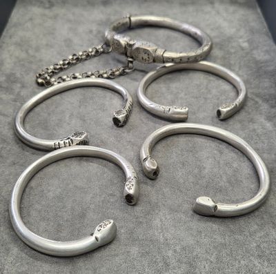plusieurs bracelets en argent et une chaîne posés sur une table
