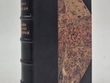 un vieux livre à la couverture noire posé sur une table blanche
