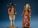 two figurines of a man and a woman dressed in period clothing