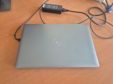 a dell laptop sitting on a table with a charger plugged into it