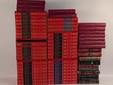 plusieurs livres rouges empilés les uns sur les autres sur une surface blanche