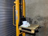 a forklift with a coffee cup on it in front of a garage door