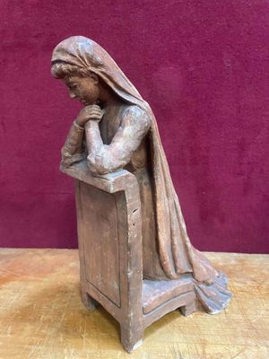 wooden statue of a woman sitting on a bench with her hands folded over her head