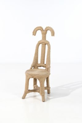 une petite chaise en paille dont le dossier est orné d'une tête de chèvre