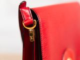 the red purse is open on a wooden surface with a gold clasp
