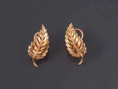a pair of gold earrings on a black background