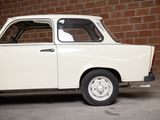 a small white car that is parked in front of a brick wall