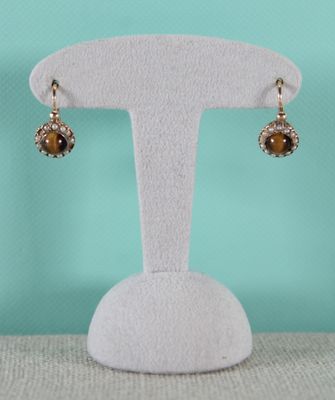 a close up of a pair of earrings on a display stand