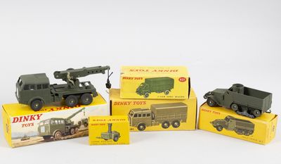 Plusieurs véhicules militaires miniatures sont posés sur des boîtes, sur une surface blanche.