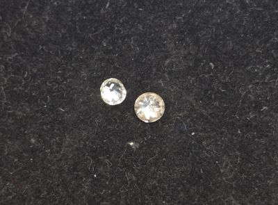 a pair of diamond stud earrings on a black surface