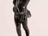 a small statue of a boy holding a bird on a pedestal