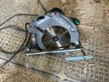 a circular saw sitting on the ground next to a piece of wood