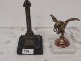 a statue of a bird on a pedestal next to a statue of a bird on a pedestal