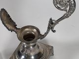 a silver vase and a silver spoon on a table