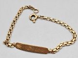 a gold bracelet with an engraved bar on it