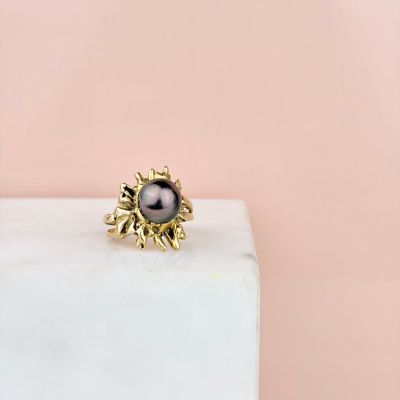 une bague ornée d'une perle noire posée sur un bloc de marbre blanc