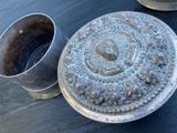 un récipient en métal posé sur une table à côté d'une tasse