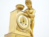 a gold clock with a statue on top of it