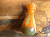 orange and green vase sitting on top of a wooden table