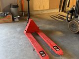 un chariot élévateur dans un garage, avec une palette au premier plan