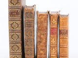 plusieurs vieux livres sont alignés sur une surface blanche
