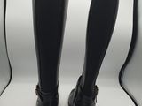 two pairs of black boots that are on a white surface